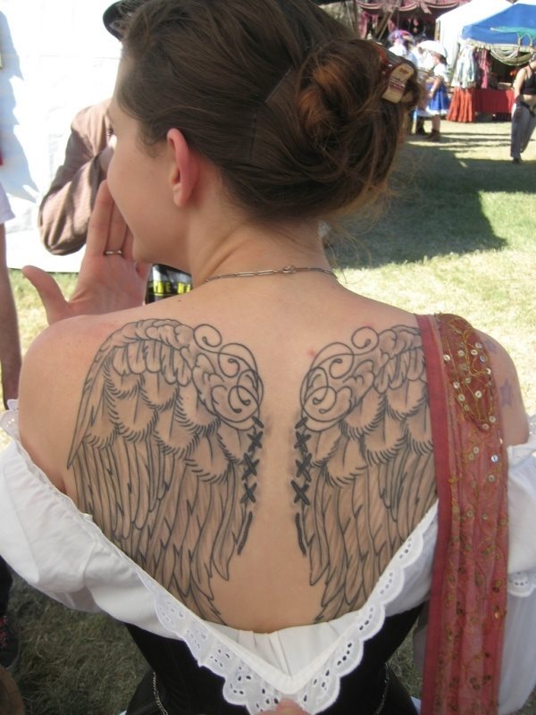 Tatuaje en la espalda de unas alas que parecen estar cosidas a la propia espalda, no nos gustan demasiado el dibujo de las ecnegas que tiene en la parte superior, pero sí el toque que le dan las costuras a las alas