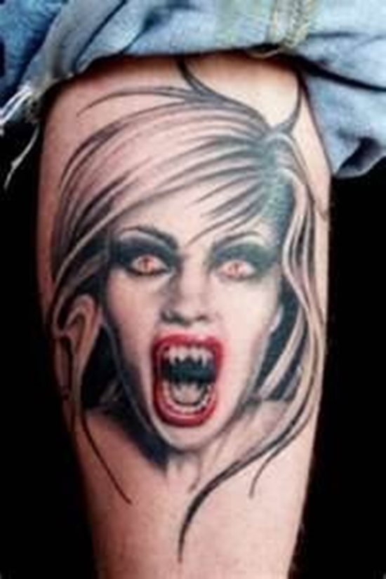 Tatuaje de una vampira en negro, para el que sólo se ha destinado el color rojo a tatuar los labios de esta mujer, del que sobresalen unos afilados colmillos muy característicos de los vampiros