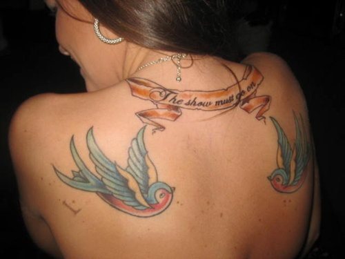 Dos bonitas golondrinas simtricamente tatuadas en la parte superior de la espalda