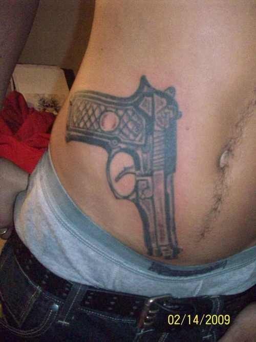 Tatuaje de una pistola sobre el abdomen, tal vez en el sitio donde se llevaría una pistola de verdad, pero este chico quiere ser más pacífico y ha decidido que en vez de una pistola de verdad, llevaría una tatuada para así proclamar la paz, estamos convencidos que ese es el sentido del tatuaje