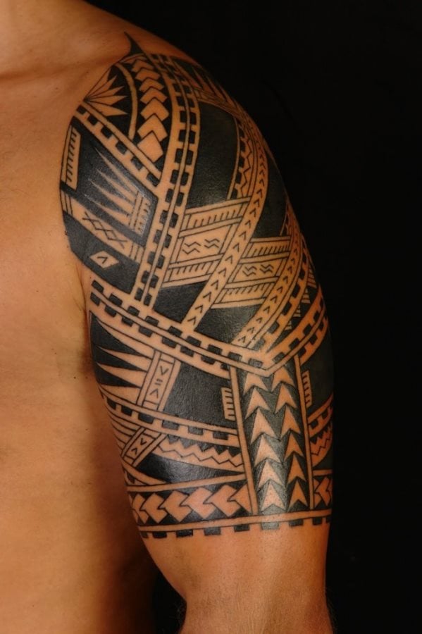 Tatuaje de cenefas de estilo azteca cubren todo el hombro, tríceps y bíceps de este chico