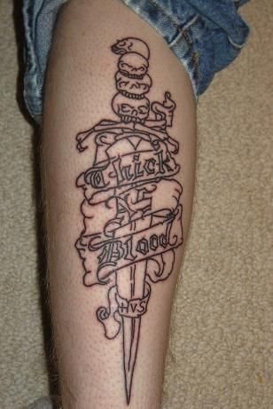 Tattoo de una espada con un mensaje alrededor tatuada en la pierna
