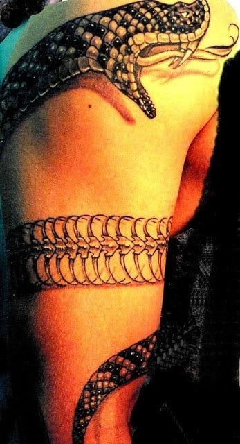 La serpiente de esta tatuaje rodea el brazo y muestro, a trozos, su esqueleto