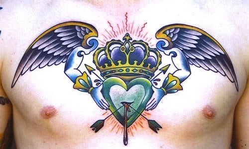 Tatuaje de un corazón cruzado con flechas y del que sale un pequeño goteo de sangre, el corazón está presidido por una corona dorada y azul, con dos alas que tienen brazos y que agarran el corazón, un tatuaje muy original y con un colorido muy bonito, ya que la mezcla de azul y dorado le da un resultado genial