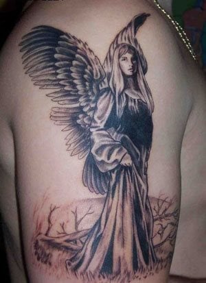 Tatuaje de una mujer con largo vestido de seda y unas grandes alas, sobre un fondo de árboles quemados o secos y que han catapultado a este tatuaje a ser uno de los mejores tataujes de ángel que hemos visto, muy serio y muy detallado