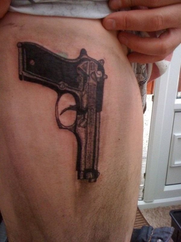 Tattoo sobre la pierna de una pistola de gran calibre para el que el color negro ha sido el único utilizado en el diseño y dibujo de este tatuaje