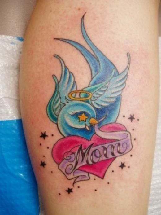 Bonito tatuaje de un corazón rojo coronado y con unas grandes las de color celeste, en cuyo interior del corazón podemos apreciar un lazo morado con las palabras mum a color negro y franqueado por unas pequeñas estrellas y puntos negros