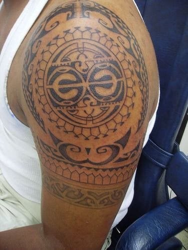 Tatuaje circular de tipo azteca tatuado sobre el hombro, para el que resalta el gran sol azteca que se ha trazado en el centro del tatuaje, rodeado por unos muy buenos y finos adornos aztecas en color negro