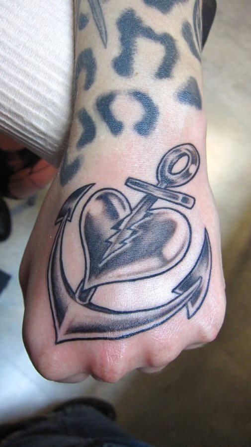 Tatuaje de un ancla clavado en un corazón y que lo parte en dos y es que el amor es a veces así, como un ancla que te parte el corazón para toda la vida, pero estamos seguros que son pocas las heridas que se pueden sanar, así que ánimo