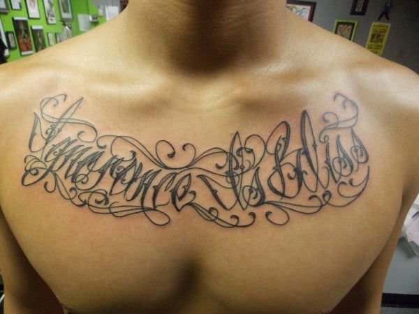 Tatuje en el pecho que no nos gusta demasiadpo porque se han tatuado demasiadas cenefas alrededor y sobre las palabras que se han tatuado en el pecho, impidiendo que estas palabras se puedan ver con nitidez, formando en conjunto un garabato poco legible