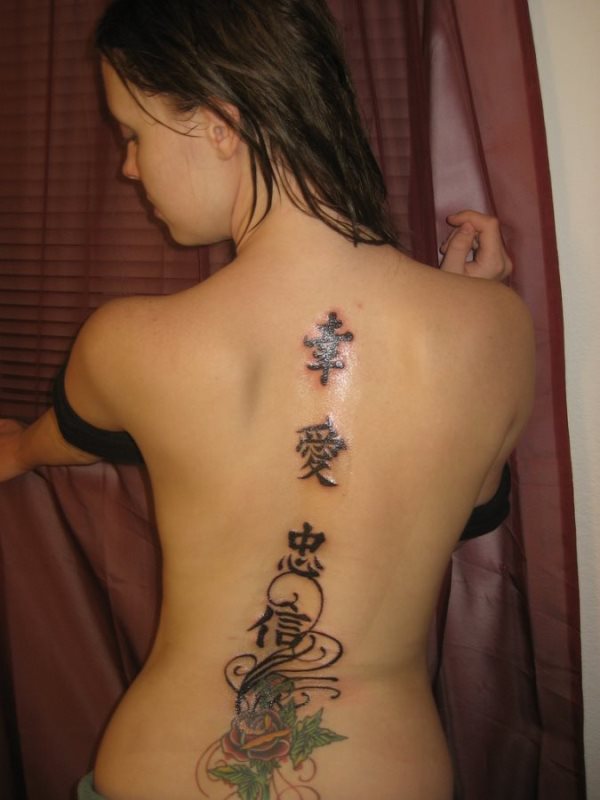Tatuaje en la espalda de tres letras chinas en la posición de la columna vertebral, que culminan en la zona de la cintura con una rosa roja de hojas verdes y adornadas con florituras de cenefas
