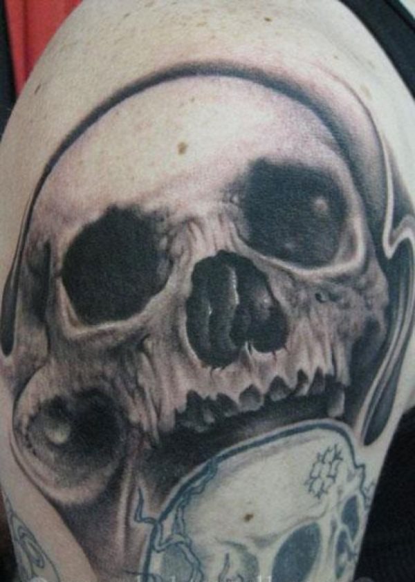 Tatuaje de una calavera con una especie de orejas, no sé como se les ha podido ocurrir, sobre otra valavera que parece inacabada e incompleta