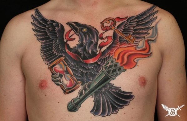 Tatuajede im águila negra sobre el pecho y acompañado el águila de un lazo sobre el cuello con una llave antigua, en una de sus patas lleva un reloj de arena y en la otra agarra una antorcha de gran tamaño, al que se le ha tatuado un poco de humo