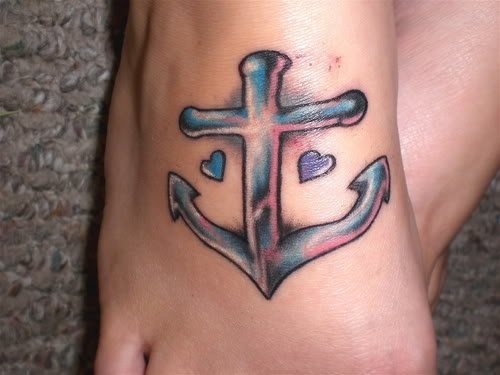 Tatuaje en el empeine de un ancla flanqueado por dos pequeños corazones del mismo color que el ancla, en esta ocasión se han optado por unos colores para este diseño que hacen que parece que el ancla sea de verdad de metal, muy bonito sin duda