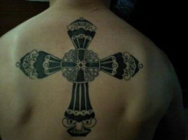 Original y elaborada cruz negra sobre la espalda de este tatuado, una cruz que nos gusta mucho porque no es la típica cruz que acostumbramos a ver, si nos fijamos en la gran cantidad de detalles con los que cuenta este tatuaje, nos daremos cuenta que estamos ante un gran tattoo