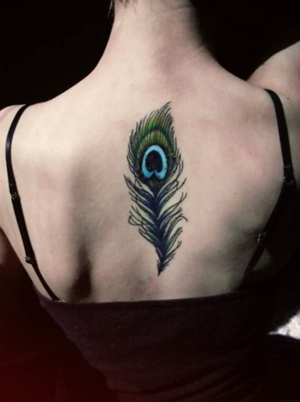 Tatuaje en la espalda de una pluma de pavo real en tonos verdes y con el centro característico en color turquesa, la verdad es que vemos y disfrutamos de la delicadeza con la que ha sido tatuado este bonito dibujo
