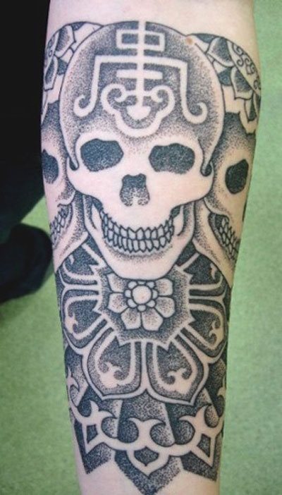 Tatuaje de calavera muy original, gracias a los otros dibujos que completan la calavera, que si nos fijamos son tres calaveras exactamente iguales pero con distinto dibujo sobre el craneo, un buen trabajo que nos gusta bastante, por encontrar la originalidad en el diseño de calaveras, además los motivos florales con los que remata el tatuaje al final le da un aspecto súper bonito