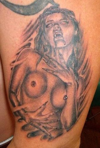 Tatuaje de una mujer vampiro con los senos al descubierto, a la que se le ha dibujado sangre sobresaliendo de la boca y unas grandes uñas