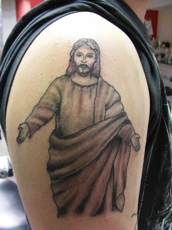Tatuaje en el brazo del cuerpo y cara de Cristo, aunque la idea es muy buena, el dibujo en sí no es de los mejores tatuajes que hemos visto, además se ha resaltado demasiado las líneas que componen el trazo del dibujo