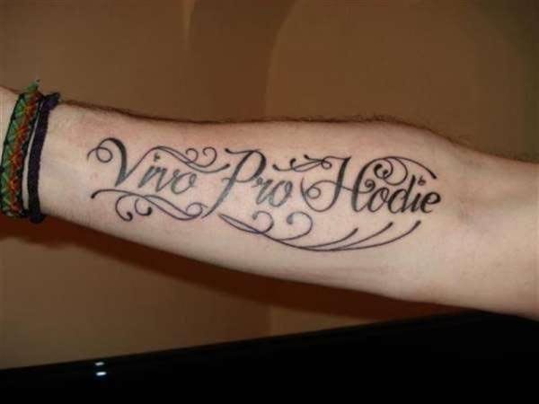 Tatuaje en el entebrazo de una frase que esta persona ha querido dejar marca para siempre y que ha rodeado con unas cenefas, algunas salen de las propias letras capitales y otras se han tatuado bajo la frase