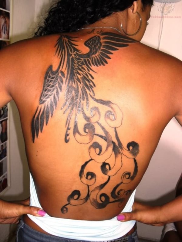 Tatuaje en la espalda de una mujer para el que se ha optado por un ave con trazos que nos recuerdan a los tribales, gracias a la forma que se le ha dado a las plumas y alas, además se observa como hay algunas cenefas que van bajando por la espalda