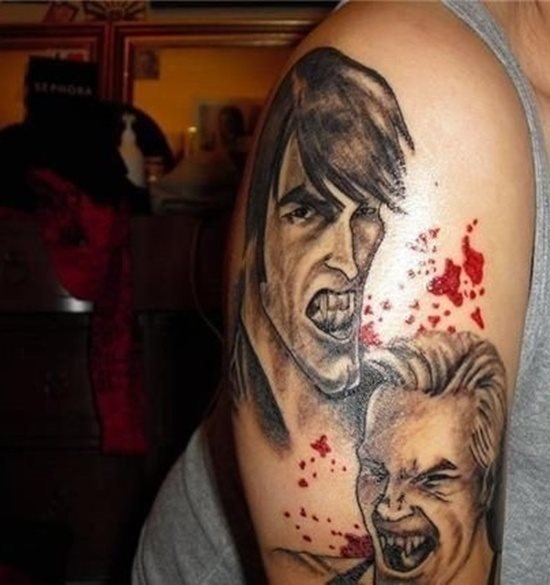 Tatuaje en el brazo de dos hombre vampiros a color negro, para el que se ha dejado el color rojo para pintar restos de sangre alrededor de todo el tatuaje