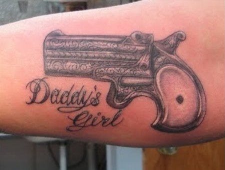 Pistola con el mensaje tatuado debajo: 