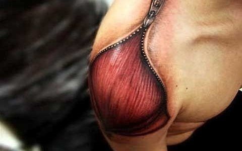 Espectacular tatuaje en el homnro de una cremallera que parece abrir la propia piel y dejar al descubierto los tendones y músculos