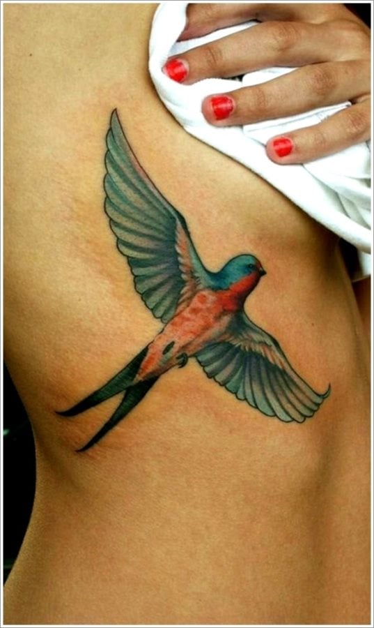Tatuaje de una colorida y viva golondrina en pleno vuelo con unas espectaculares alas totalmente abiertas hacen de este tattoo una obra de arte, en la que el sombreado de las alas nos gusta bastante y los colores elegidos aún más