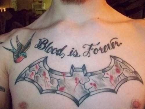 Tatuaje del símbolo de Batman en el pecho con acabado de piedra, grietas y restos de sangre, y sobre el que se ha tatuado la frase Blood is forever, junto a este tattoom otro tatuaje de una pequeña golondrina, que tal vez no pegue demasiado con el murciélago, pero que da un aspecto bonito al conjunto del cuerpo de este hombre