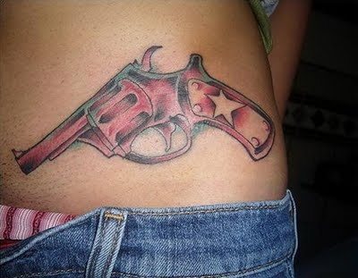 A un lado del abdomen se ha tatuado este revolver a color rojo, para el que se ha dibujado una estrella asimétrica sobre la culata de la pistola