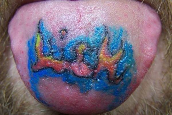 Tatuaje de unas pequeñas llamas en la lengua, para la que se ha realizado un fondo azul acabado en dos pequeños cuernos sin silueta