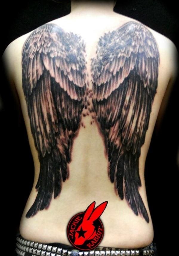 Tatuaje de unas enormes alas sobr ela espalda de esta chica, alas que están compuestas en su parte inferior por plumas de gran tamaño y largas, que cada vez se van haciendo más pequeñas conforme vamos observando la parte de arriba de las alas