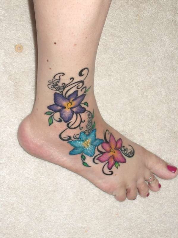 Flores de colores vivos en el pie de una mujer, un tatuaje clásico y atemporal, de buen gusto y con ganas de mirarlo sin parar, en este caso vemos como a cada flor le ha acompañado de un nombre, seguro que son personas muy importantes para esta chica tatuada y por ello ha decidido dejar marca de ello para siempre