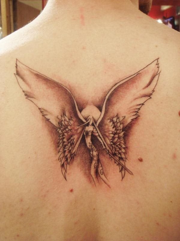 Tatuaje de una mujer con unas alas enormes en comparación al cuerpo del ángel y que de fondo se aprecia como una especie de sol, al que el sombreado le acompaña muy bien y que ha dado como resultado uno de los más originales tatuajes de ángel que hemos visto
