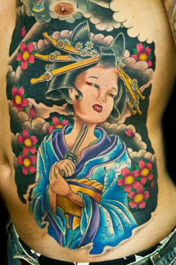 Geisha con un cuchillo sobre el cuello que ocupa gran parte del pecho y vostadode este chico, un tatauje muy bien confeccionado con un fondo muy bueno de color negro y adornado con unas flores muy bien tatuadas, al igual que la confeccion de la geisha que ha sido ideal, como es el peinado que lleva tan bien conseguido y con unos brillos estupendos