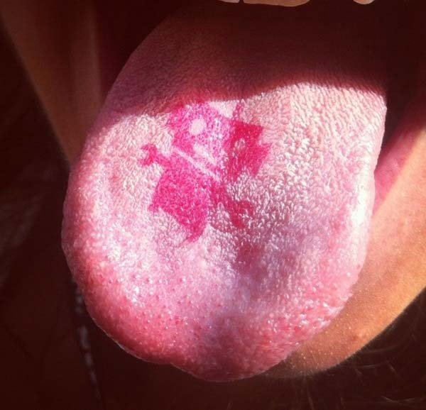 Tatuaje de un pequeño marciano en el centro de la lengua, u ntatuaje en rojo muy simpático y original, que evidentemente no puede tener un tamaño demasiado grande porque la lengua no es un músculo demasiado grande ni demasiadi fácil para tatuar