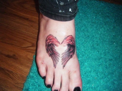 Tatoo en el empeinede unas alas en tonos rojizos y sombreado en negro que oarecen formar un corazón por los espacios que se han dejado en el centro sin tatuar, un peculiar tatuaje en una zona muy escogida por las chicas para hacerse un tatuaje