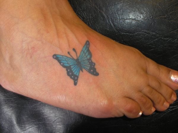 Pequeo tatuaje de una mariposa azul en el empeine del pie