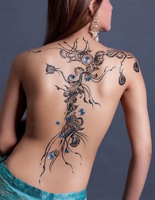 Tatuaje en la espalda de unas flores que empiezan en el hombro, bajan por la columna vertebral y terminan en la cintura