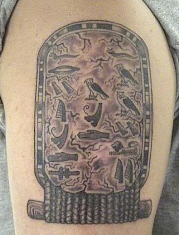 Peculiar y distintivo tatuaje de motivos egipcios a color negro sobre el brazo, en este tatauje podemos ver motivos típicos egipcios tales como las aves u otros caracteres