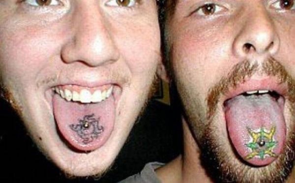 Estos dos chicos han decidido acompañar su piercing en la lengua con un pequeño tatuaje en la lengua alredeor de su pendiente, un de ellos parece una espeice de sol o de estrella en colores verdes y amarillo, mientras que el otro tatuaje en la lengua parece una especie de tribal sin rellenar