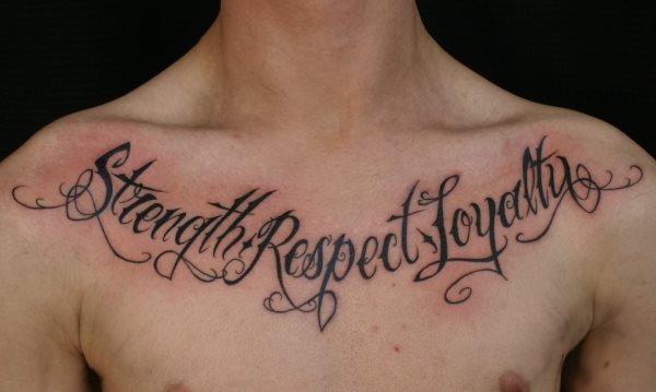 Tatuaje en el pecho de corte clásico, formado por uan frase realizad con letras de tipografía sencilla con adornos muy rectangulares en el acabado de las cenefas, sin apenas separación entre letras y palabras