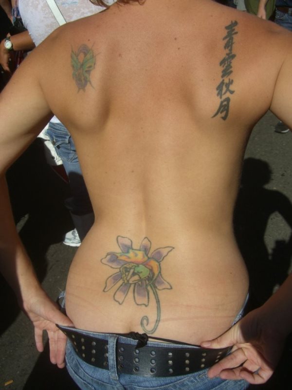 Esta chica tiene una mariposa tatuada en el omóplato izquierdo, mientras que en el omóplato derecho se ha tatuado una palabra en letras chinas de manera vertical y en la cintura tiene un tatuaje de una enorme flor