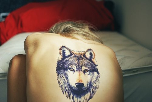 Esta chica lleva la cabeza de un lobo tatuada en el centro de su espalda