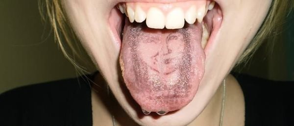 Tatuaje de la silueta de una chica tatuada en la lengua, como se puede observar no son unos trazos demasiado definidos ya que en esta parte del cuerpo debe ser muy difícil trazar un tatuaje