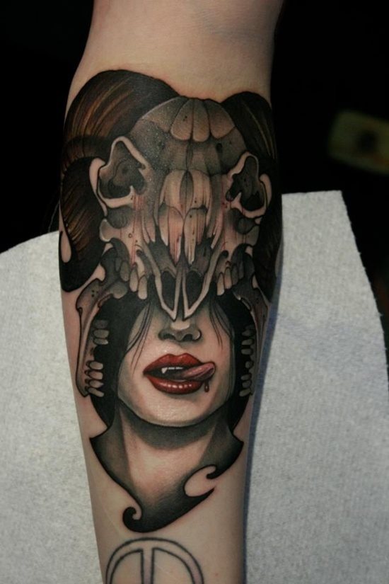 Tatuaje de una mujer vampira que parece estar disfrutando de una buena dosis de sangre, esta mujer aparece representada con un enorme casco del craneo de algún animal con cuernos, posiblemente una cabra