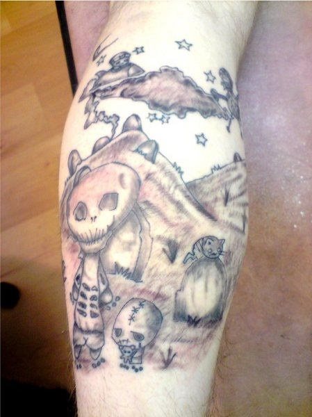 Tatuaje de unas montañas con lápidas y nubes con estrelas y pequeñas naves espaciales, donde los protagonistas son varias calaveras y un gatito, sin duda, un tatuaje muy original, de gran acierto la zona escogida