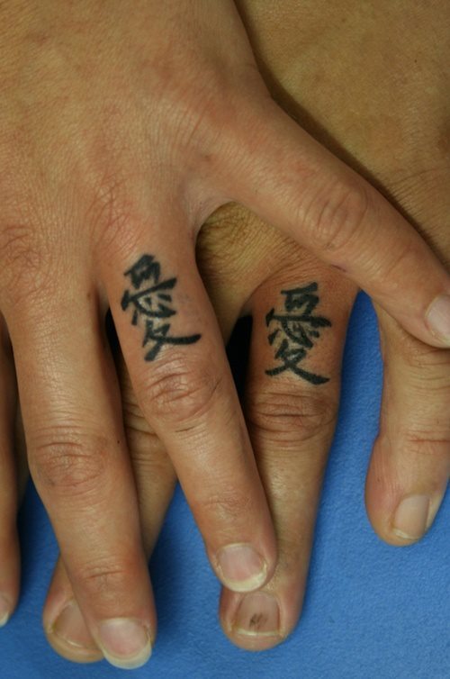 Smbolos chinos en un dedo de una mano y en el dedo de otra mano