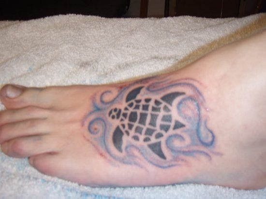 En la siguiente imagen nos encontramos con un tatuaje situado en el empeine de esta persona, en el cual se puede ver la silueta de una tortuga que nada entre unas aguas con remolinos
